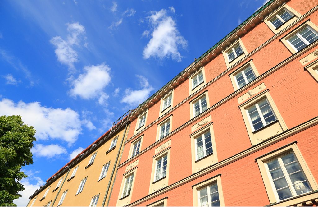 Lägenhetshus med fasad i gult och orange mot en blå himmel