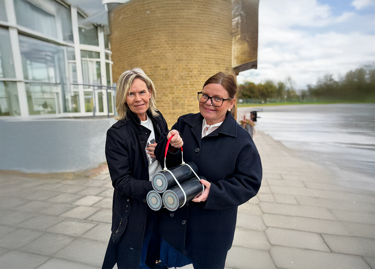 Våra medarbetare Åsa och Anna håller en bit av en 130-kilovoltskabel mellan sig.