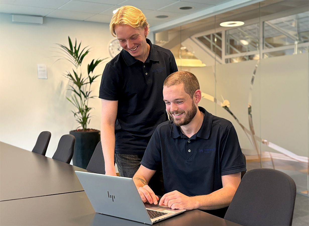 IT-kollegorna pratar och ler när de tittar på en datorskärm.