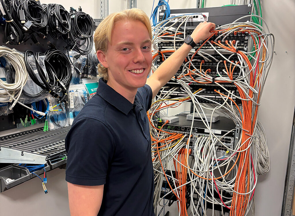 IT-tekniker Albin står framför switchar med kablar.